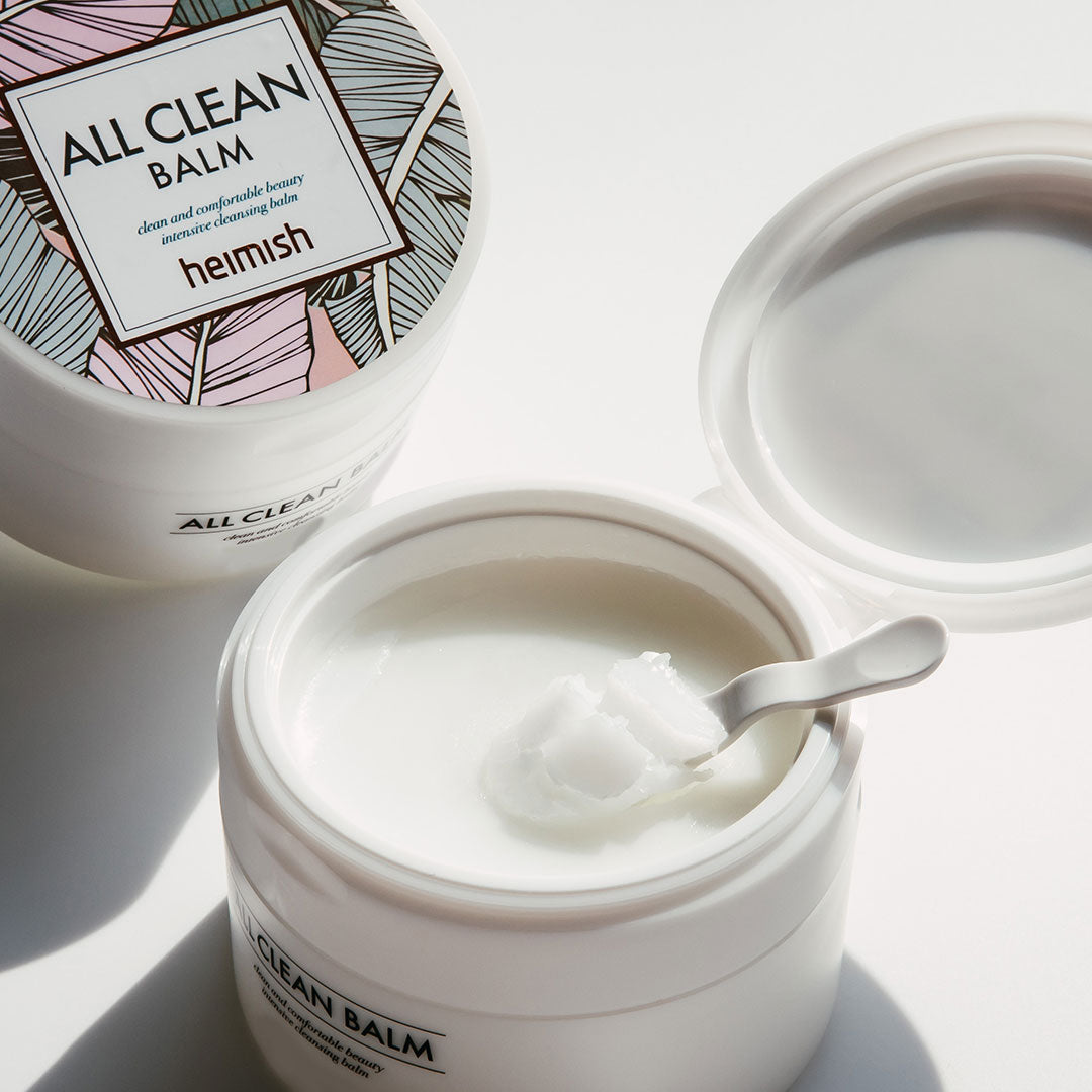 Open jar of 'All Clean Balm' with a spoon inside, next to a closed jar and packaging.