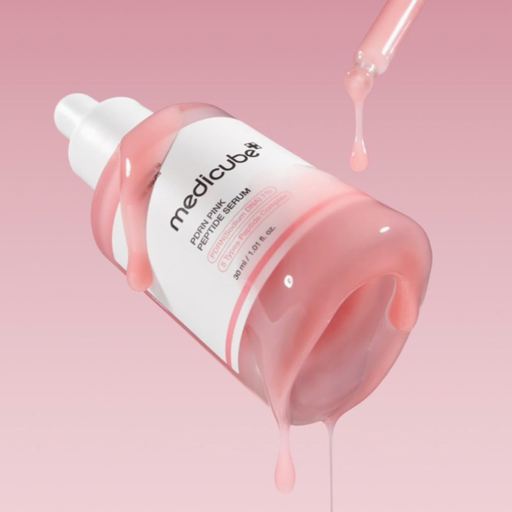 Medicube pink serum bottle with pink serum on a pink background